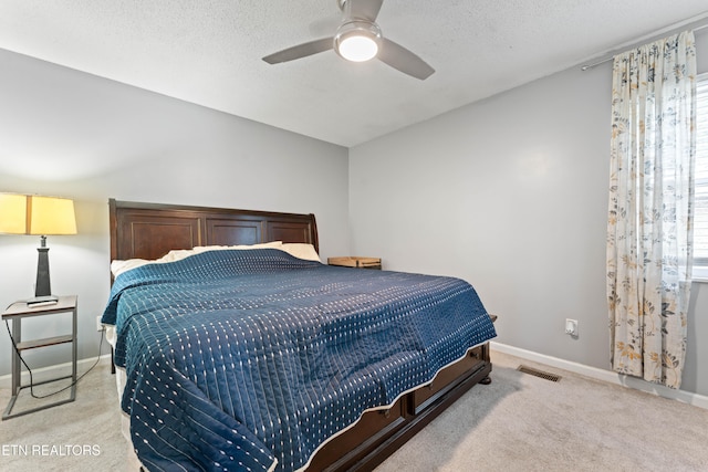 bedroom with ceiling fan, a textured ceiling, and light carpet