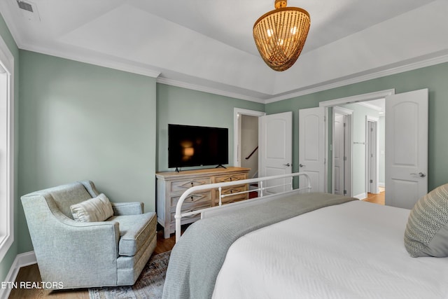 bedroom featuring hardwood / wood-style floors, a raised ceiling, and crown molding