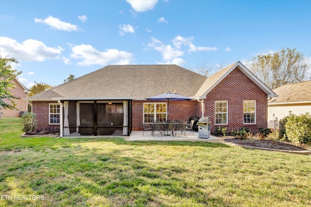 rear view of house featuring a lawn, a patio area, and a sunroom