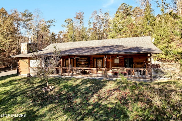 rear view of house with ceiling fan and a yard