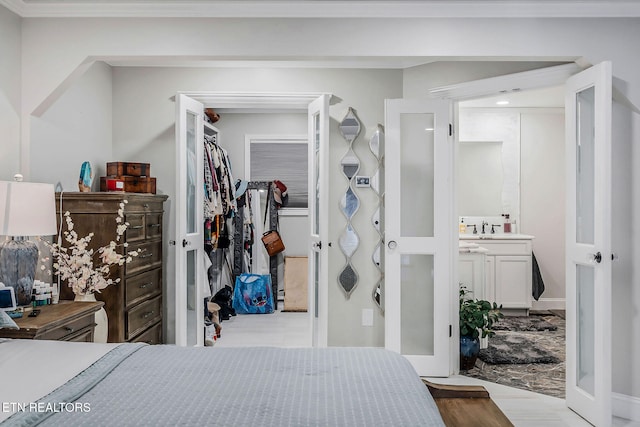 bedroom with ornamental molding, light hardwood / wood-style floors, sink, and a closet