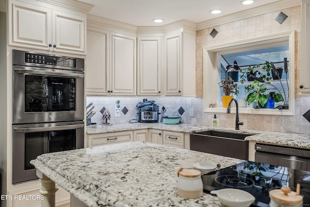 kitchen with stainless steel double oven, light stone counters, sink, and backsplash