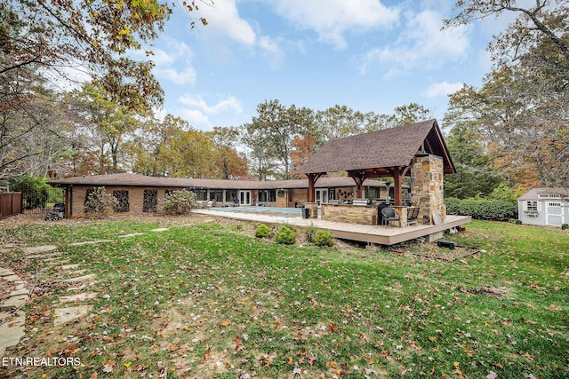 back of house with a storage shed, a wooden deck, a lawn, and a gazebo