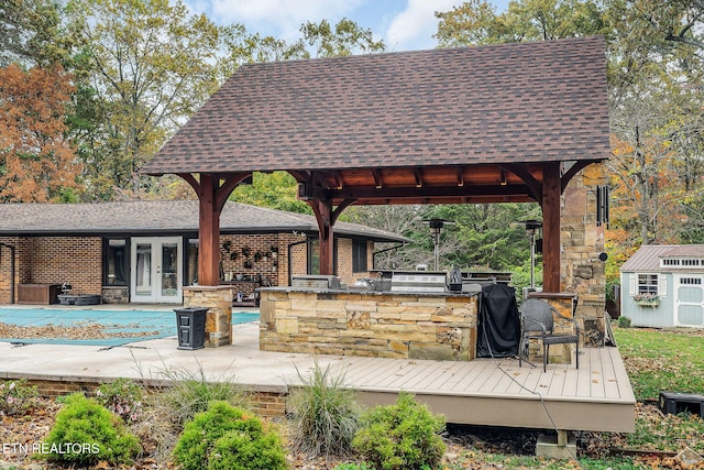 exterior space featuring french doors, a gazebo, a bar, a wooden deck, and a storage shed