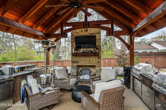 view of patio / terrace featuring an outdoor stone fireplace, a gazebo, an outdoor kitchen, a grill, and ceiling fan