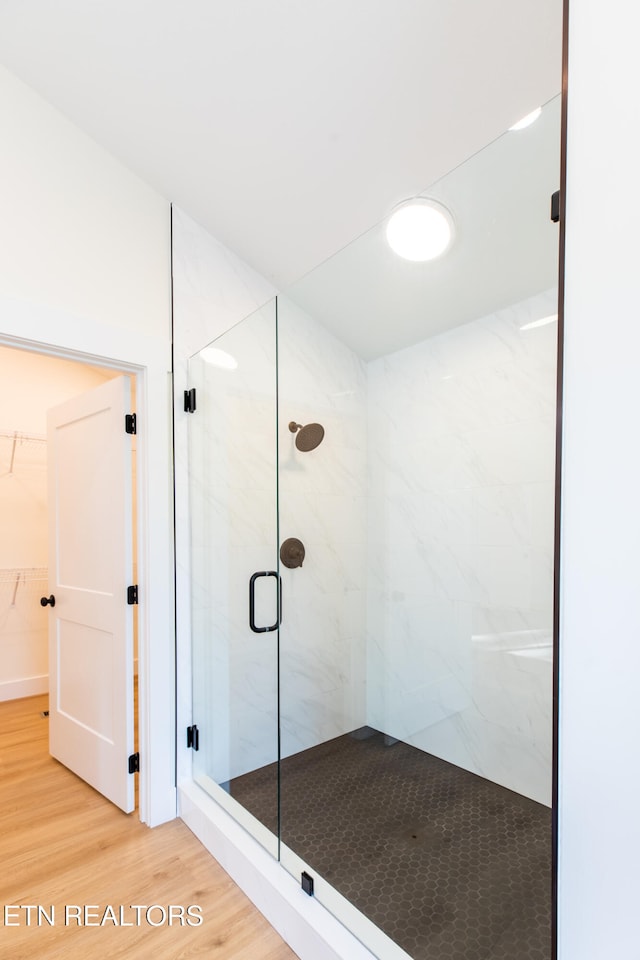 bathroom with a shower with shower door and wood-type flooring