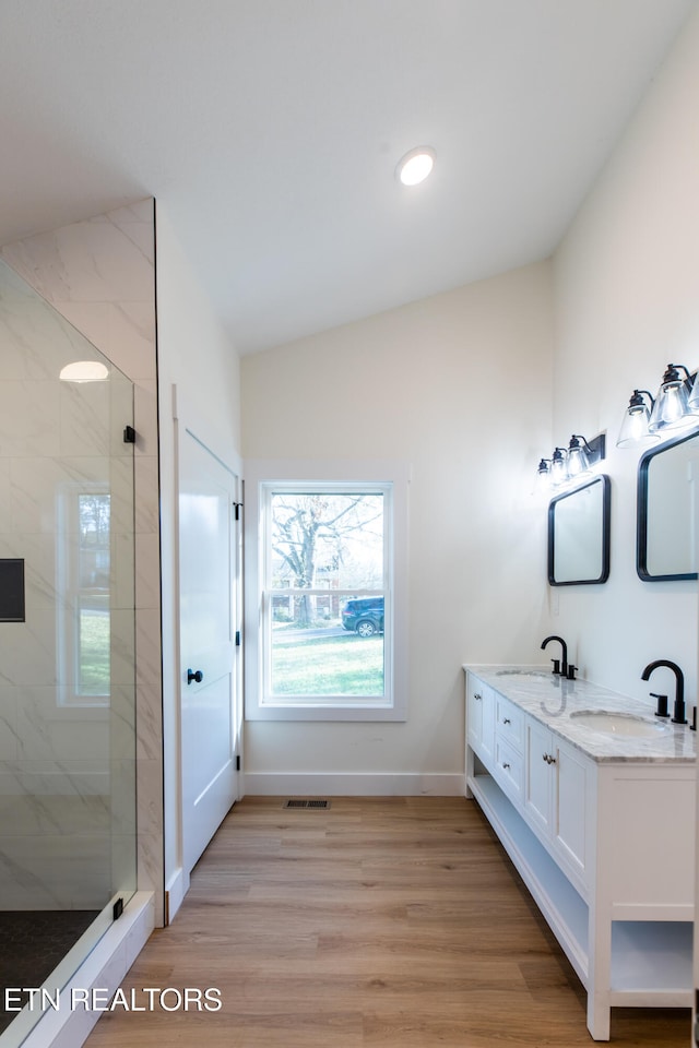 bathroom with vanity, vaulted ceiling, a shower with door, and hardwood / wood-style floors