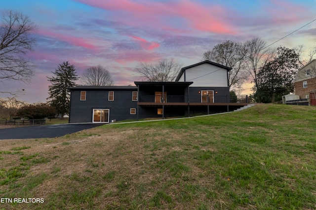 back house at dusk featuring a deck and a yard