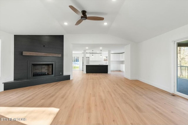 unfurnished living room with vaulted ceiling, ceiling fan, a large fireplace, and light hardwood / wood-style flooring