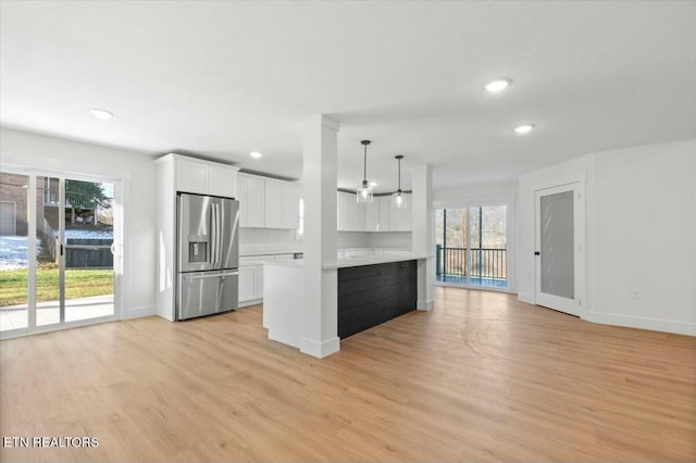 kitchen with stainless steel fridge with ice dispenser, white cabinetry, plenty of natural light, and decorative light fixtures