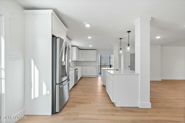 kitchen featuring white cabinetry, appliances with stainless steel finishes, light wood-type flooring, and hanging light fixtures