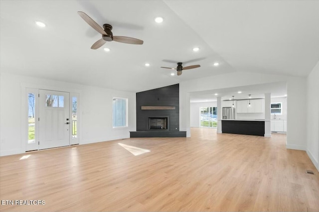 unfurnished living room featuring light wood-type flooring, ceiling fan, lofted ceiling, and a fireplace