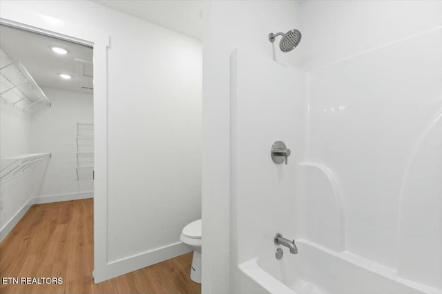 bathroom with bathtub / shower combination, hardwood / wood-style floors, and toilet