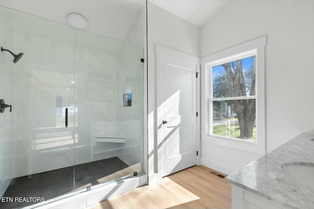 bathroom featuring tiled shower, hardwood / wood-style floors, and vanity