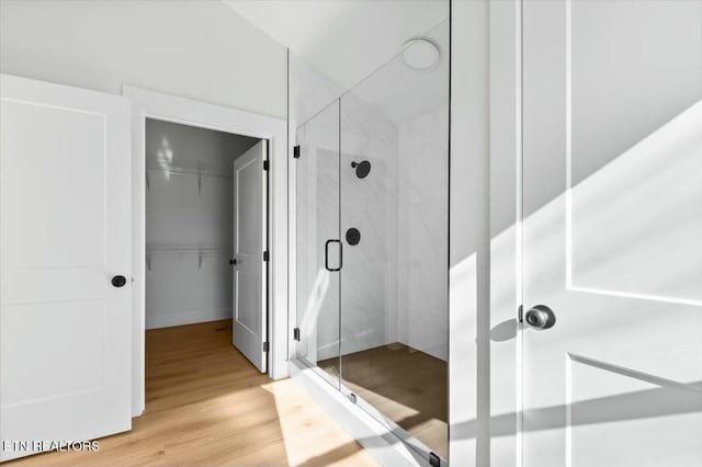 bathroom with a shower with door and hardwood / wood-style flooring