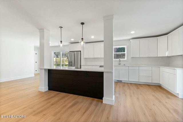 kitchen featuring a kitchen island, stainless steel refrigerator with ice dispenser, white cabinetry, light hardwood / wood-style floors, and hanging light fixtures