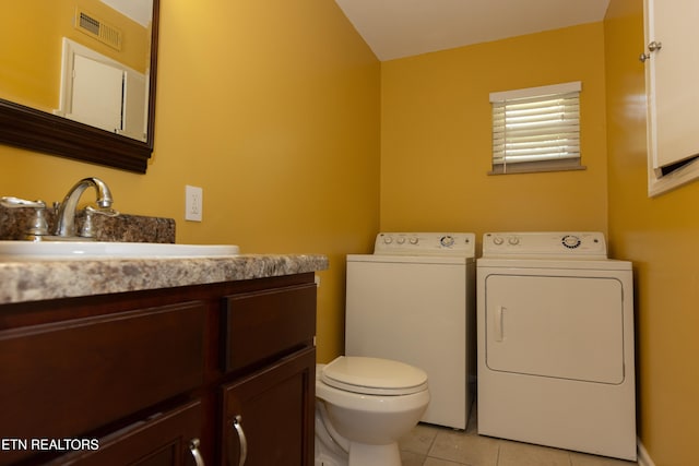 bathroom with toilet, washing machine and dryer, vanity, and tile patterned floors