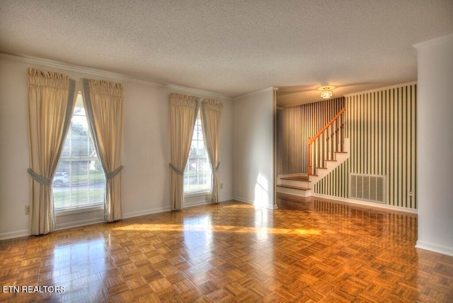 spare room featuring ornamental molding, parquet flooring, and a textured ceiling