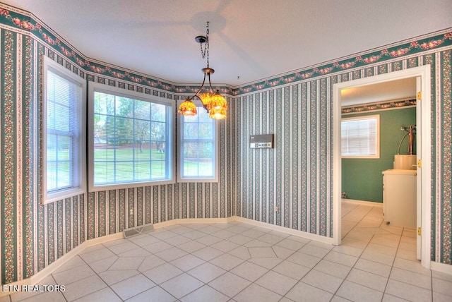 unfurnished dining area featuring a chandelier, a textured ceiling, and light tile patterned flooring