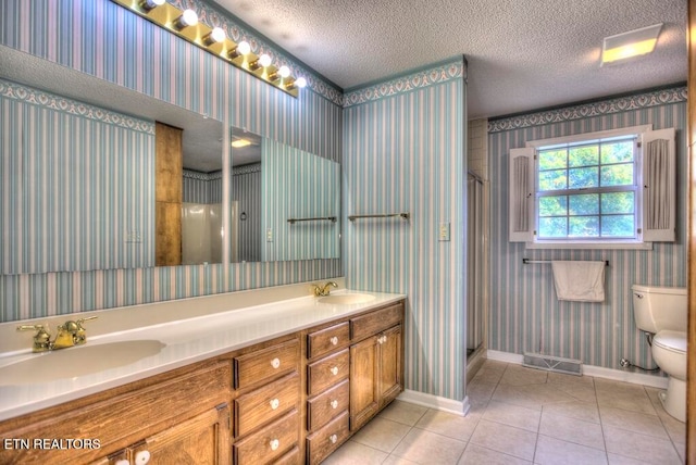 bathroom featuring toilet, tile patterned floors, a textured ceiling, vanity, and a shower with shower door