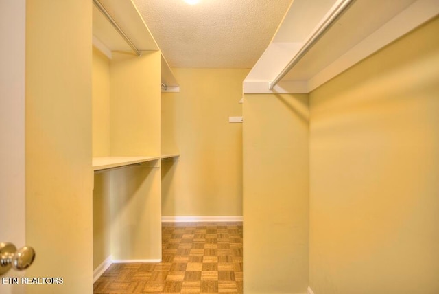 walk in closet with parquet flooring