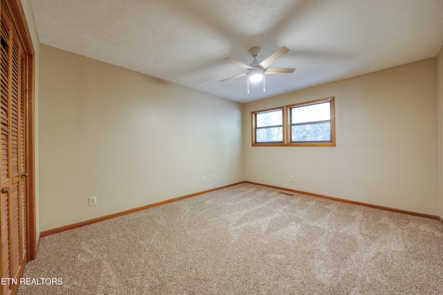 carpeted spare room featuring a textured ceiling and ceiling fan