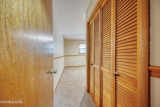 hallway featuring a textured ceiling and carpet floors