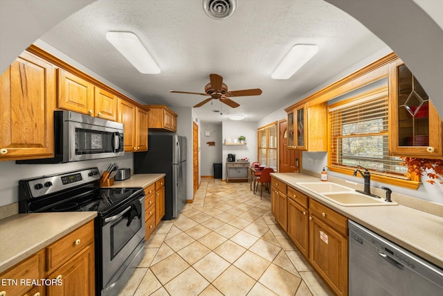 kitchen featuring stainless steel appliances, a textured ceiling, sink, light tile patterned floors, and ceiling fan