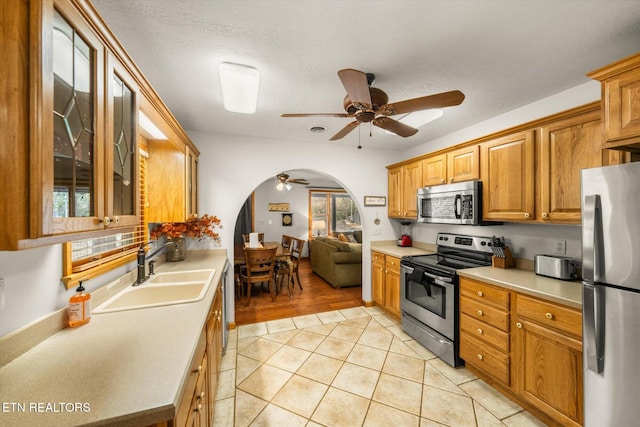 kitchen featuring light wood-type flooring, appliances with stainless steel finishes, a textured ceiling, sink, and ceiling fan