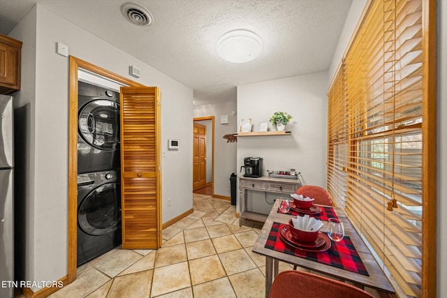 interior space featuring stacked washer / drying machine, a textured ceiling, and light tile patterned flooring