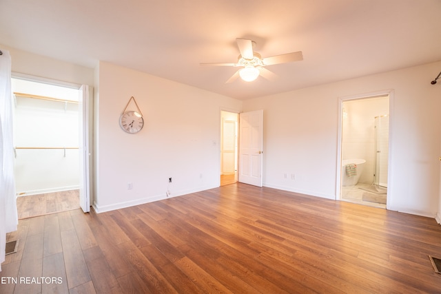 unfurnished bedroom featuring ensuite bathroom, dark hardwood / wood-style flooring, ceiling fan, and a closet