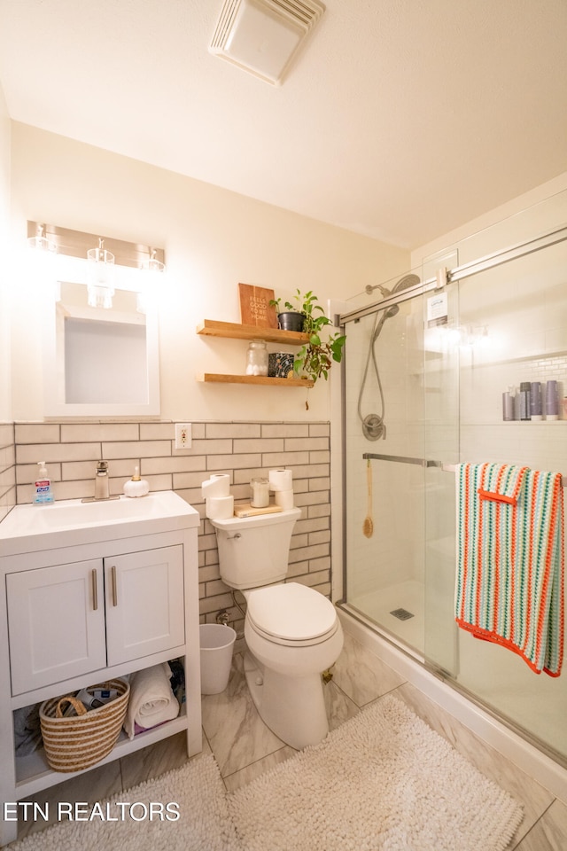 bathroom featuring walk in shower, vanity, tile walls, and toilet