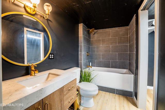 full bathroom with toilet, tiled shower / bath combo, vanity, and hardwood / wood-style floors