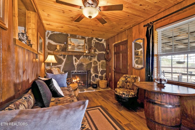 living room with wood-type flooring, wood ceiling, wooden walls, and a fireplace