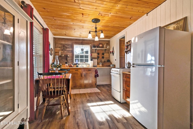 kitchen featuring hardwood / wood-style flooring, white appliances, wooden walls, and hanging light fixtures