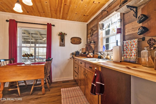 kitchen with sink, butcher block countertops, wood ceiling, wooden walls, and hardwood / wood-style flooring