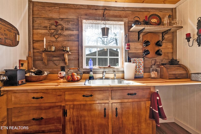 kitchen with wooden walls, decorative light fixtures, and sink