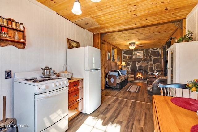 kitchen featuring dark wood-type flooring, wood walls, wooden ceiling, white appliances, and a fireplace