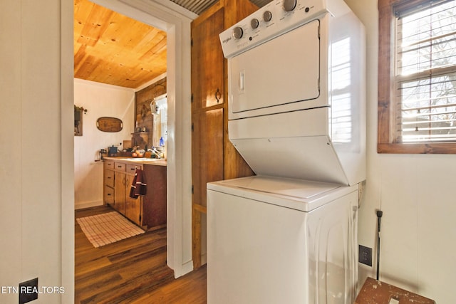 clothes washing area featuring stacked washer / dryer, dark hardwood / wood-style floors, a wealth of natural light, and wood ceiling