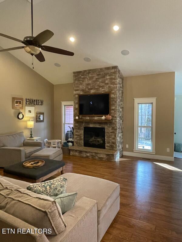 living room featuring ceiling fan, a stone fireplace, dark hardwood / wood-style flooring, and high vaulted ceiling