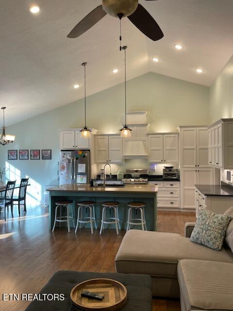 kitchen with a breakfast bar, dark wood-type flooring, sink, hanging light fixtures, and appliances with stainless steel finishes