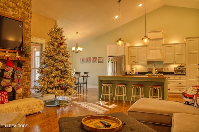 living room featuring hardwood / wood-style floors, an inviting chandelier, high vaulted ceiling, and sink