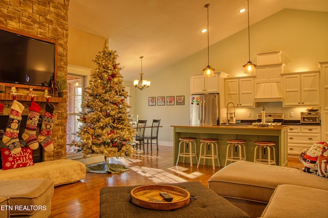 living room with hardwood / wood-style flooring, a notable chandelier, sink, and high vaulted ceiling