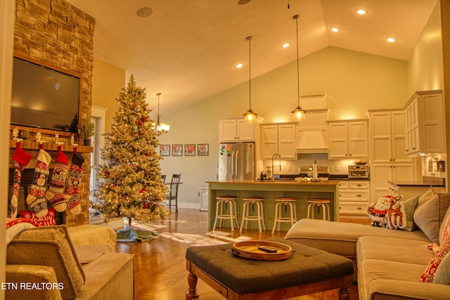 living room featuring a chandelier, light hardwood / wood-style flooring, high vaulted ceiling, and sink