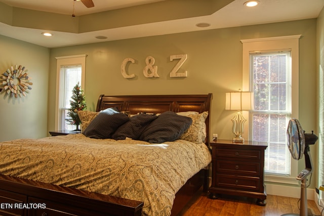 bedroom featuring ceiling fan, dark wood-type flooring, and multiple windows