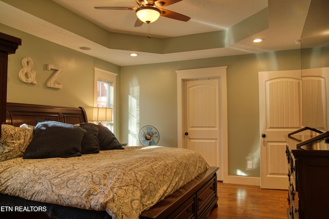 bedroom with a tray ceiling, ceiling fan, and hardwood / wood-style floors