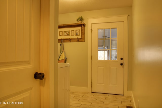 entryway with light wood-type flooring and a textured ceiling