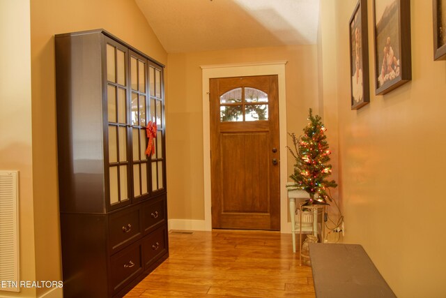 doorway with light hardwood / wood-style flooring and lofted ceiling