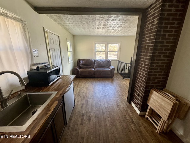 interior space with sink, beamed ceiling, dark wood-type flooring, and a textured ceiling