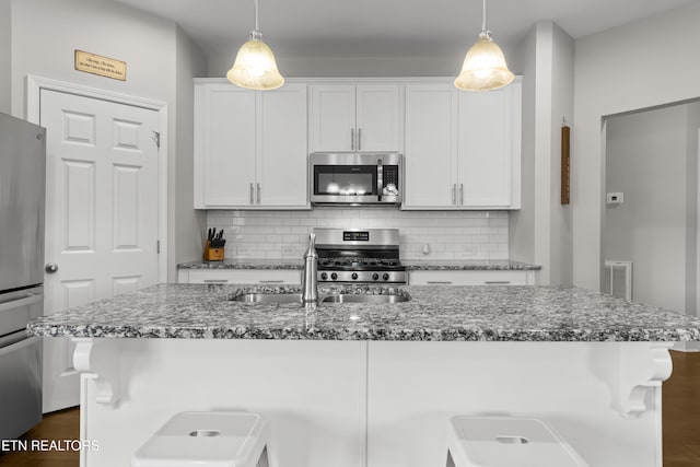 kitchen featuring white cabinets, appliances with stainless steel finishes, and hanging light fixtures